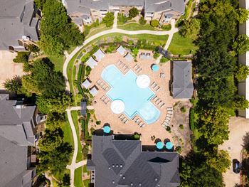 A bird's eye view of a community with a large swimming pool in the center.